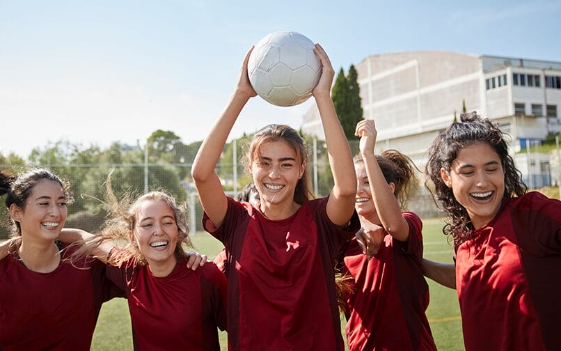 Girls smiling and holding a soccer ball